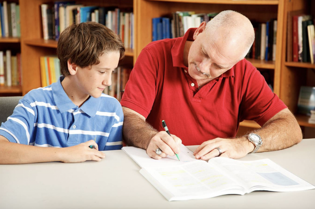 Boy in library being tutored by male teacher
