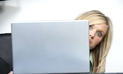 women peeking from behind computer