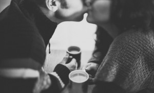 Couple holding cups of coffee and kissing