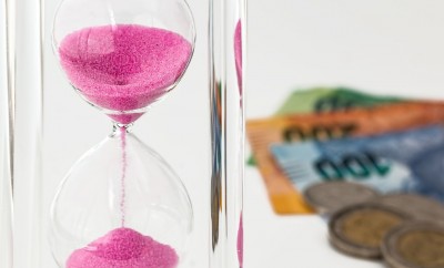 pink sand hour glass with money on background