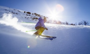 skier with yellow bottoms and blue jacket skiing down hill