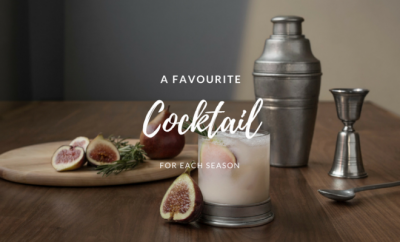 Cocktail shaker, a glass with a drink in it and figs on a brown table