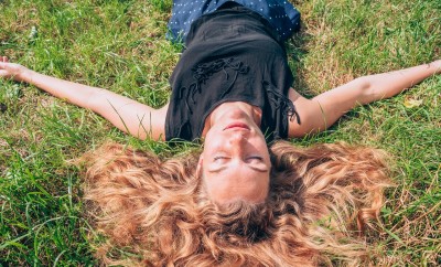 Lady with long red hair laying in the grass relaxed