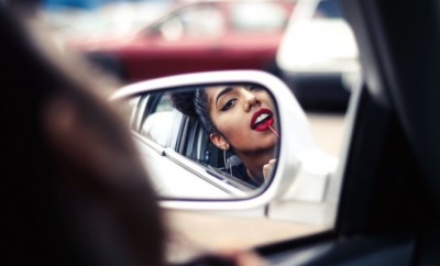 Woman driver looking into the car side mirror