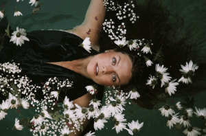 woman in clothes under water surrounded with flowers