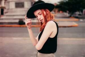 Red headed lady with black hat and tank top