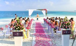 Beach wedding with pink rose petals on a white trail to the alter