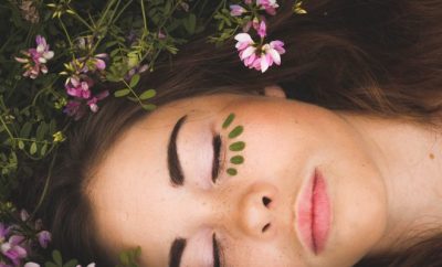 close up of a girl's face with closed eyes and flowers in her hair and