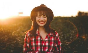 Woman wearing a hat and checker shirt smiling