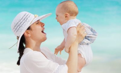 woman wearing a white hat and holding a baby up to her face