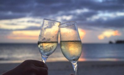 Two glasses of champagne raised in a sky horizon