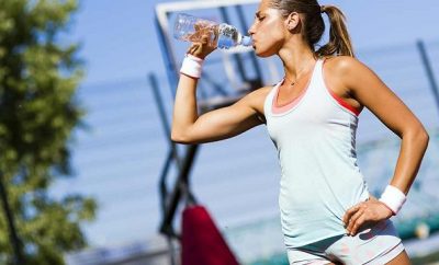 Woman in sports gear drinking mid exercise