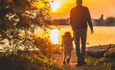 Man holding hands with a child walking in the sunset