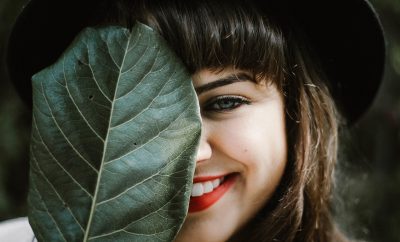Smiling woman with a large green leaf covering her face