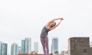 Woman stretching with a backdrop of a city behind her