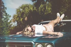 Woman lying down on the bonnet of a car