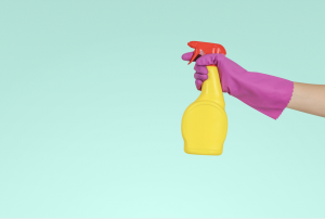 Purple gloved hand holding a cleaning spray bottle