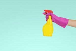 yellow cleaning spray bottle and purple gloves