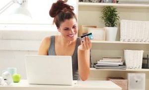 Woman in front of laptop holding her credit card, online shopping, ecoomerce