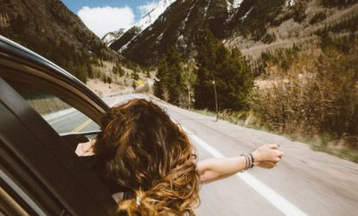 woman with head out of car window, road trip