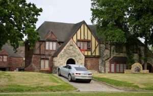 A mansion with a car parked in the drive way