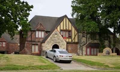 A mansion with a car parked in the drive way