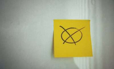 A yellow sticky note with a cross