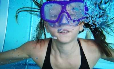 Girl with goggles swimming under water