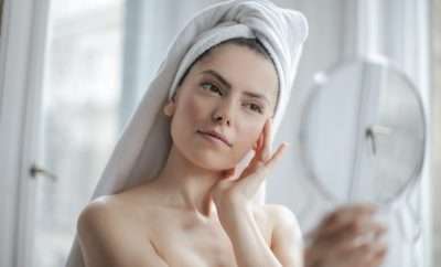 Woman with towel in hair looking at her skin