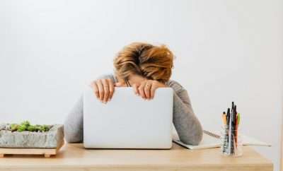 Stressed out woman leaning against laptop