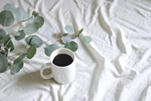 A white cup of black coffee on a white tablecloth
