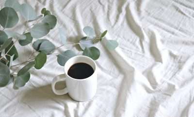 A white cup of black coffee on a white tablecloth