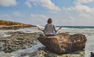 Woman in a rock at the beach meditation