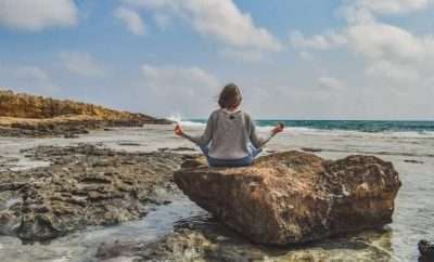 Woman in a rock at the beach meditation