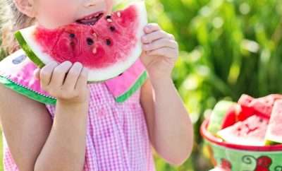 Toddler girl eating a slice of watermelon