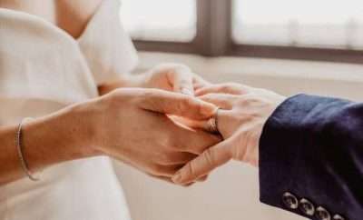 Woman putting wedding band in a man's hand