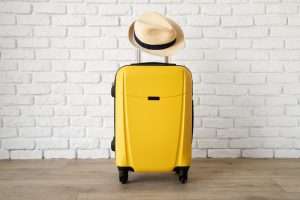 Yellow luggage with a straw hat hanging on the handle