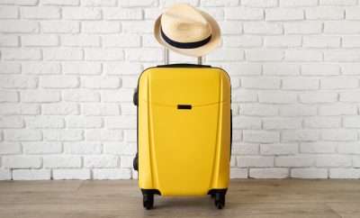 Yellow luggage with a straw hat hanging on the handle