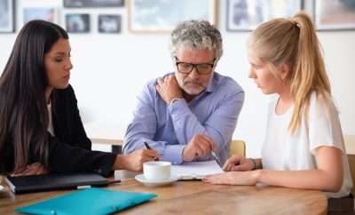 Family legal advisor explaining document details to mature father and adult daughter