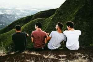 Four young man sitting os wall with a mountain horizon