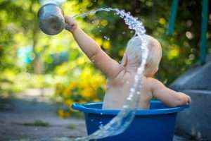 Baby splashing water in a bucket