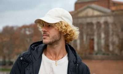 Blond curly haired man wearing a white cap
