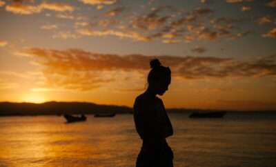Woman's silhouette with golden hues from the sky and ocean
