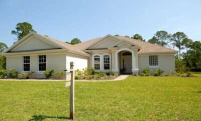 Photo of a house with a for sale sign in the front yard.