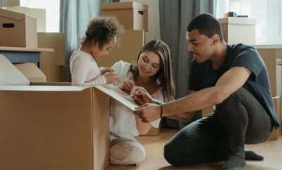 Happy family with children moving with boxes in a new apartment house